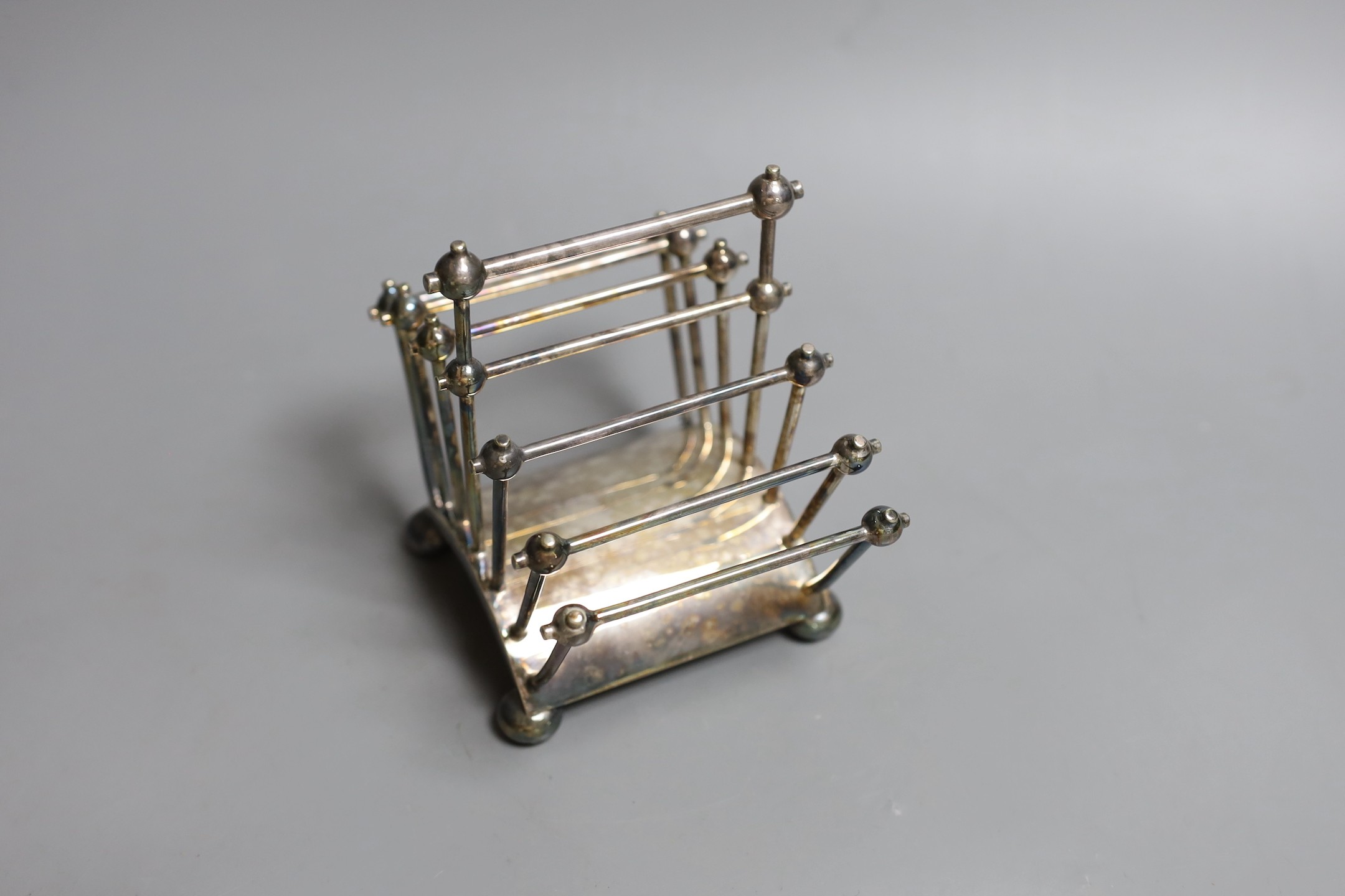 A Victorian Cristopher Dresser for Hukin & Heath silver plated seven bar toastrack, of fan shape, on bun feet, numbered 2556, width 13.5cm.